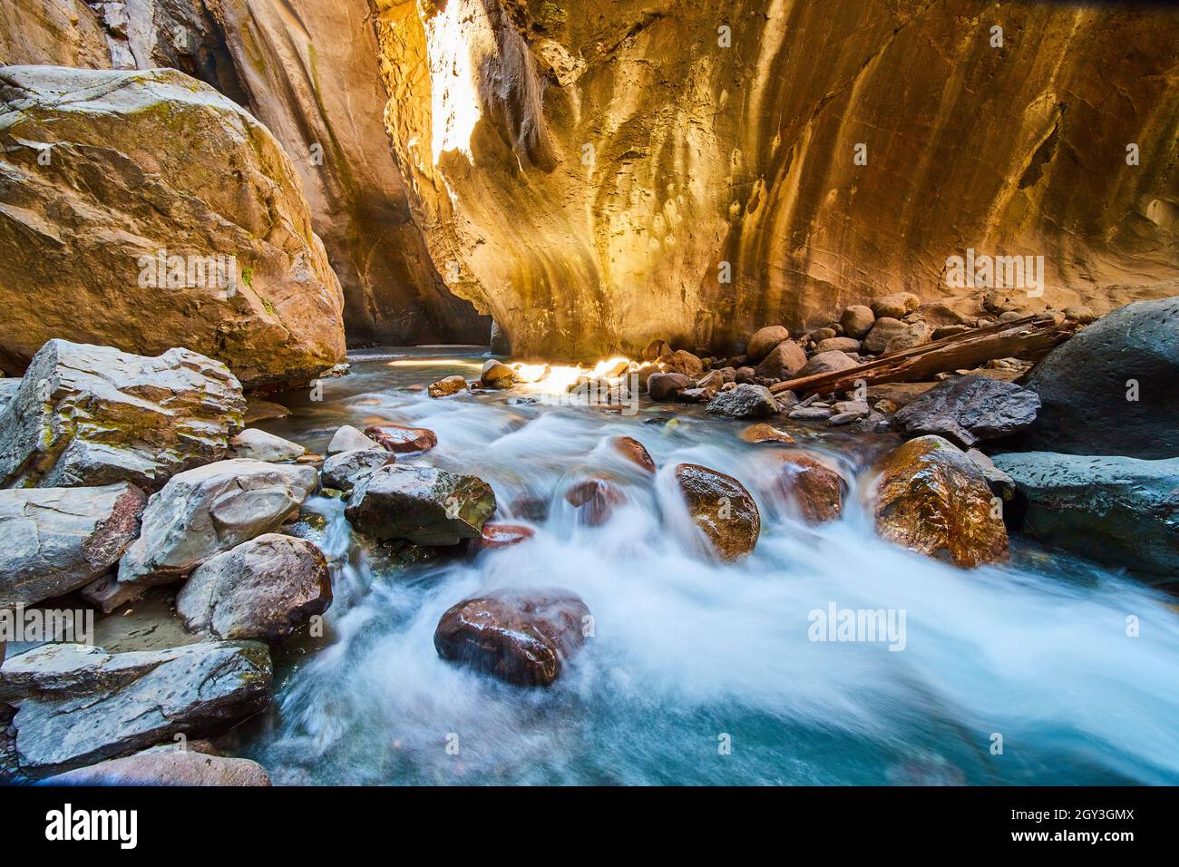 Profondo canyon gola con pareti dorate e fiume che scorre in fondo sulle rocce Foto Stock