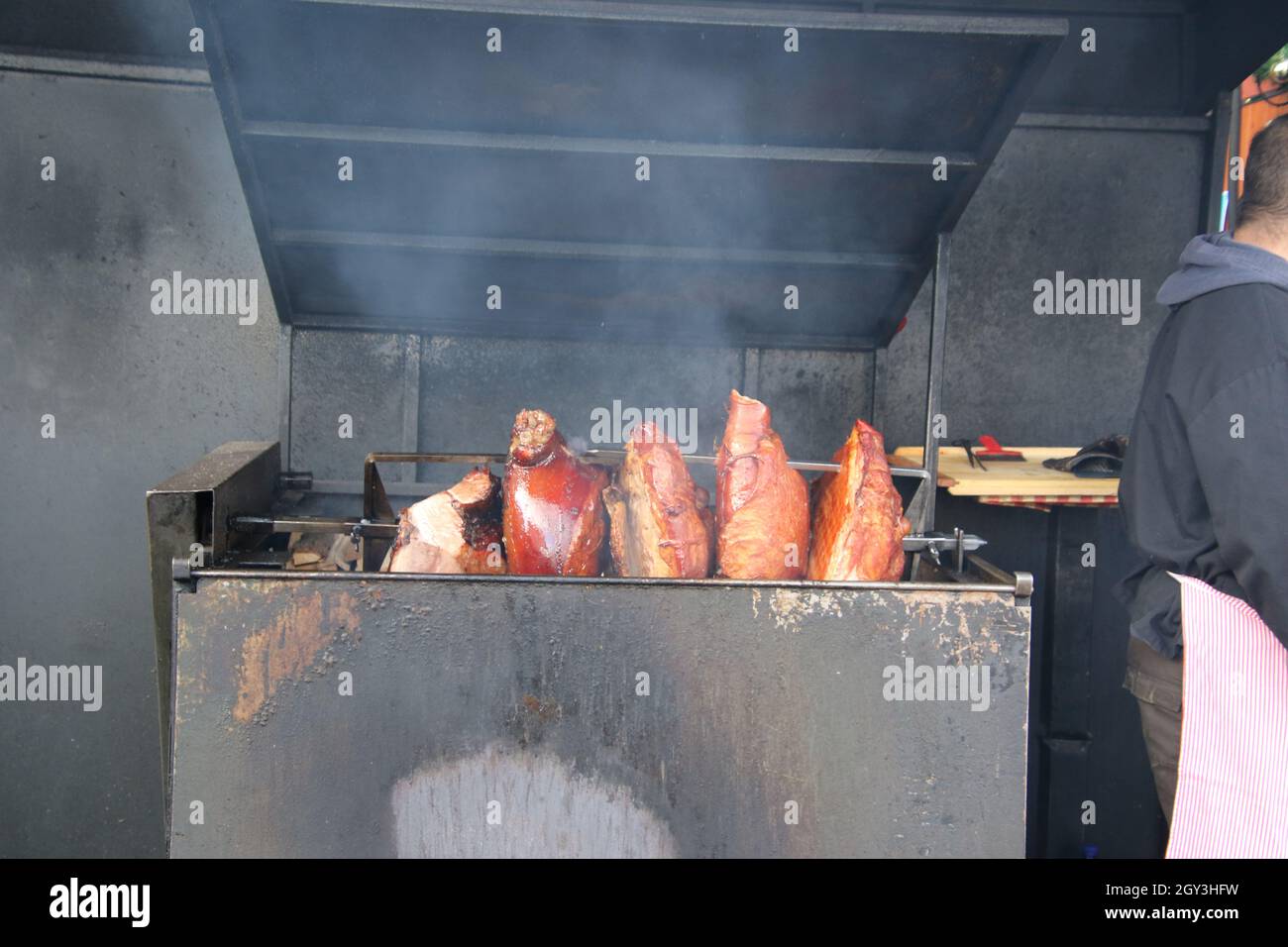 Ham si oscilla girando su una rotisserie con fumo nell'aria Foto Stock