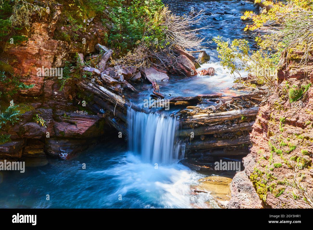 Cascata che scorre su barricata di tronchi in canyon Foto Stock