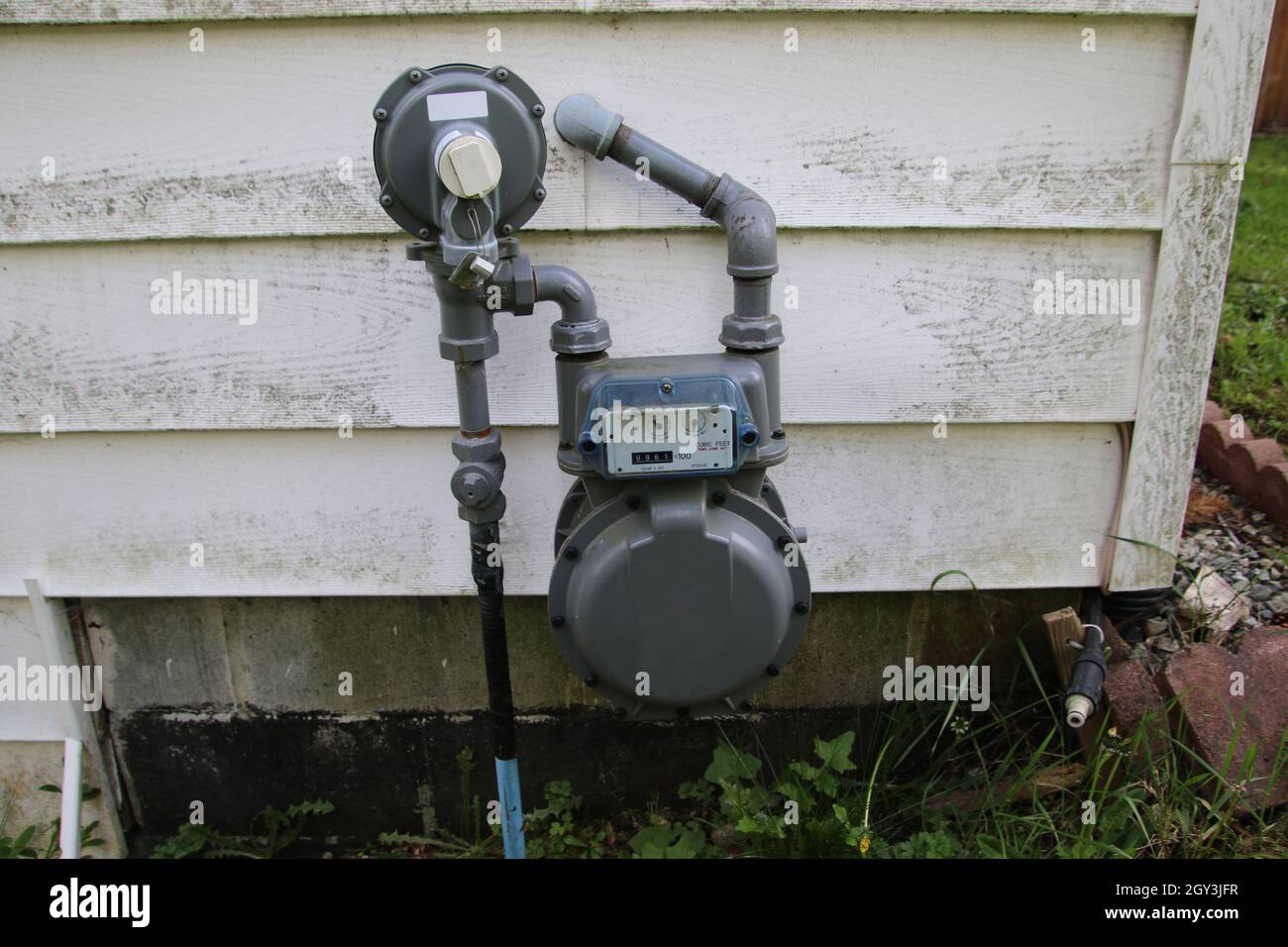 Un contatore di gas di fronte al bianco che conduce in una casa Foto Stock