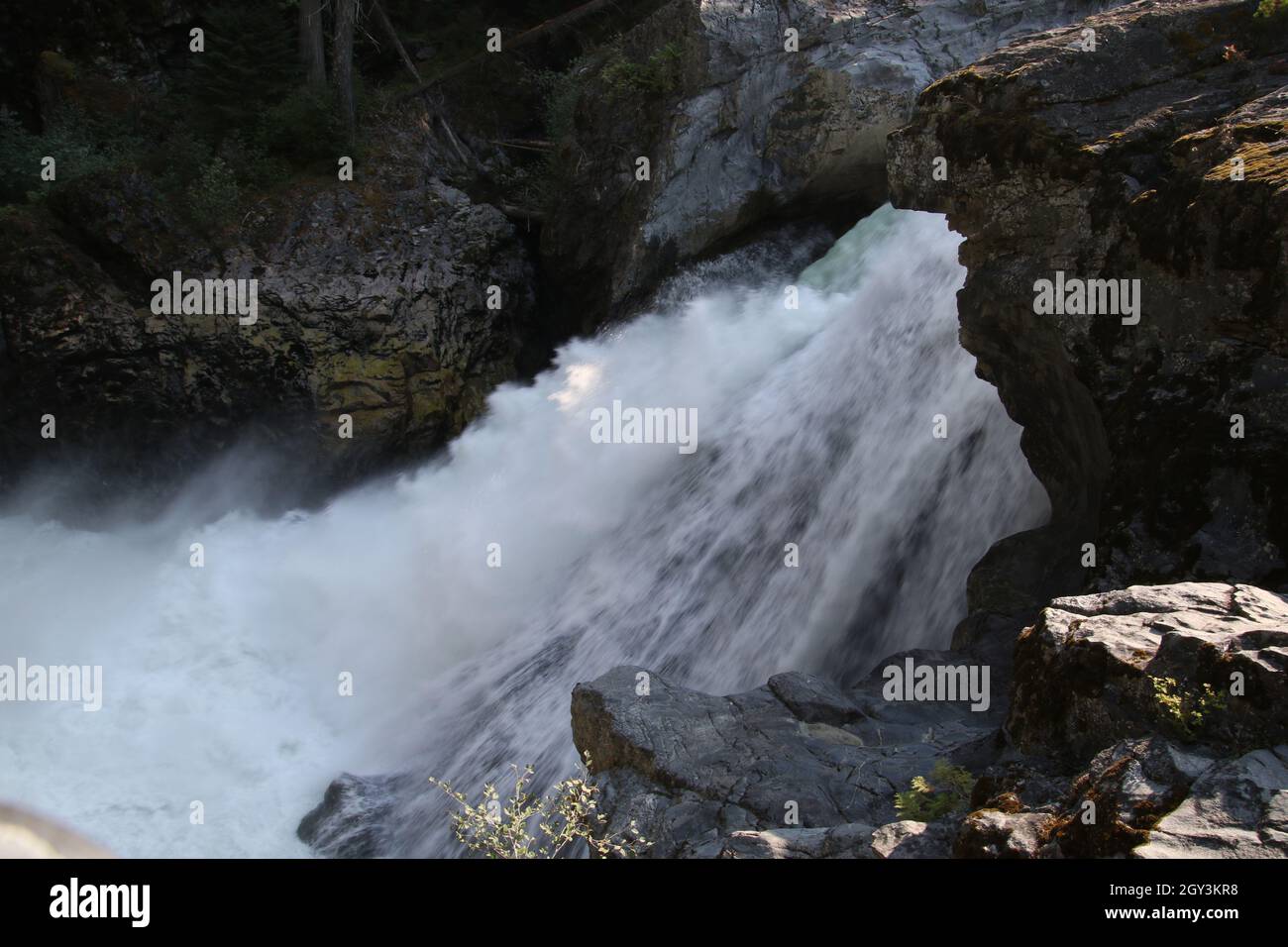 Un primo piano di cascata con l'acqua che scorre attraverso un muro di roccia. L'acqua è bianca con la schiuma di muoversi rapidamente Foto Stock