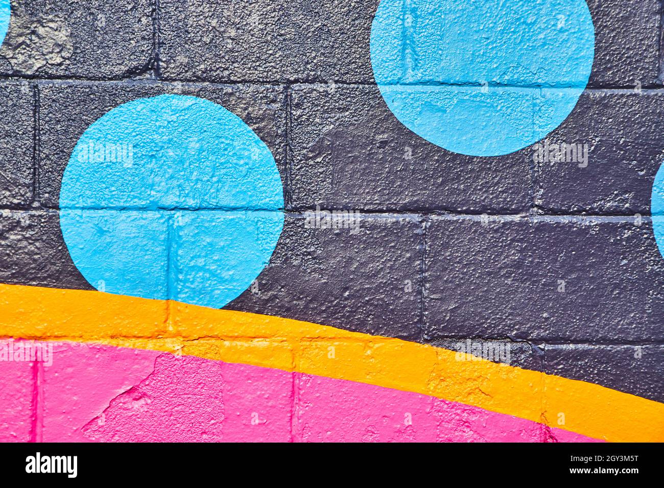 Parete di cemento dipinta con cerchi neri, arancioni e rosa e blu Foto Stock