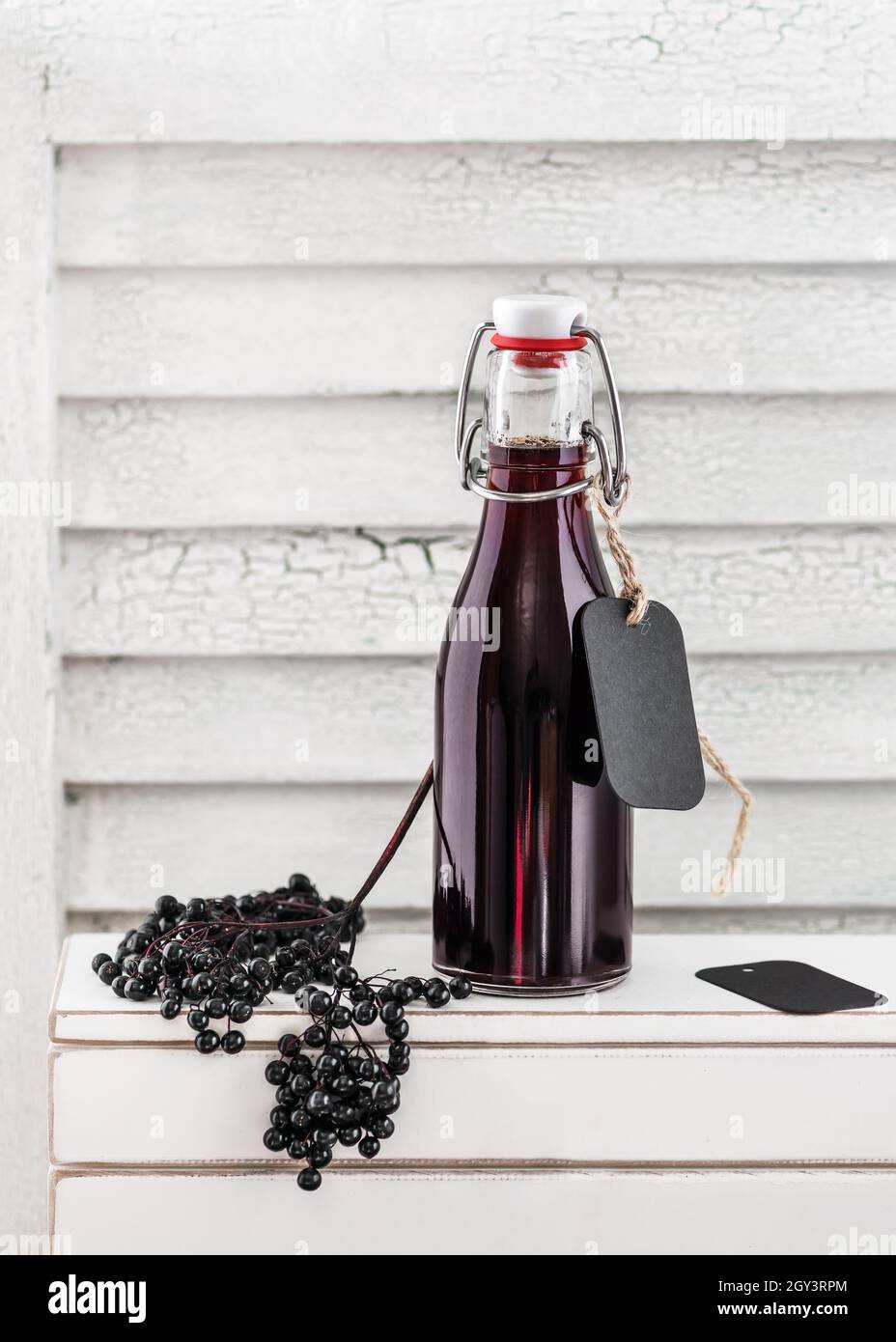 Sciroppo di sambuco nero fatto in casa in una piccola bottiglia di vetro. Concetto di bevanda di bacche d'autunno. Messa a fuoco selettiva. Spazio di copia. Foto Stock