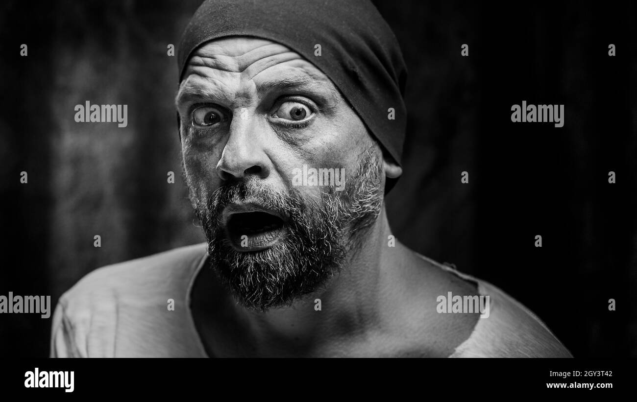 Scala di grigi girato un uomo bearded con un'espressione scioccata del volto Foto Stock