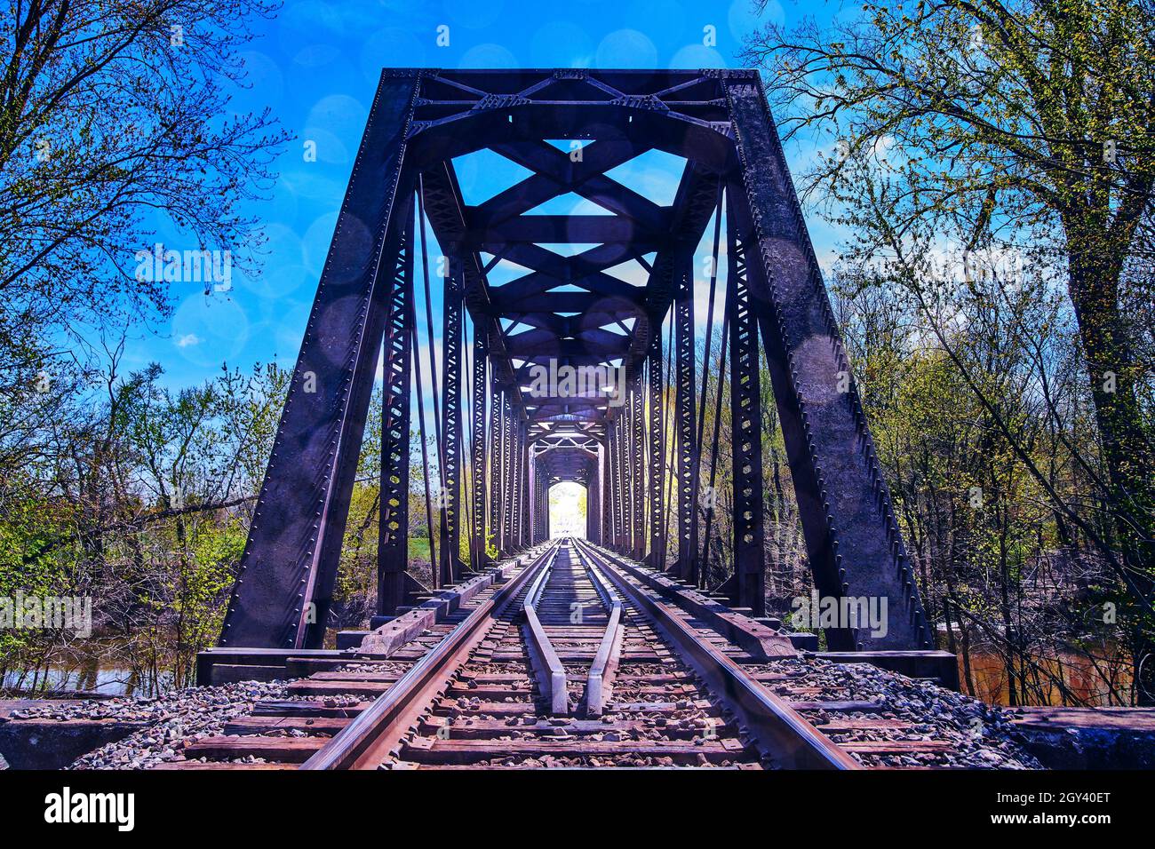 Treno di binari attraverso il vecchio ponte con luce luminosa alla fine Foto Stock