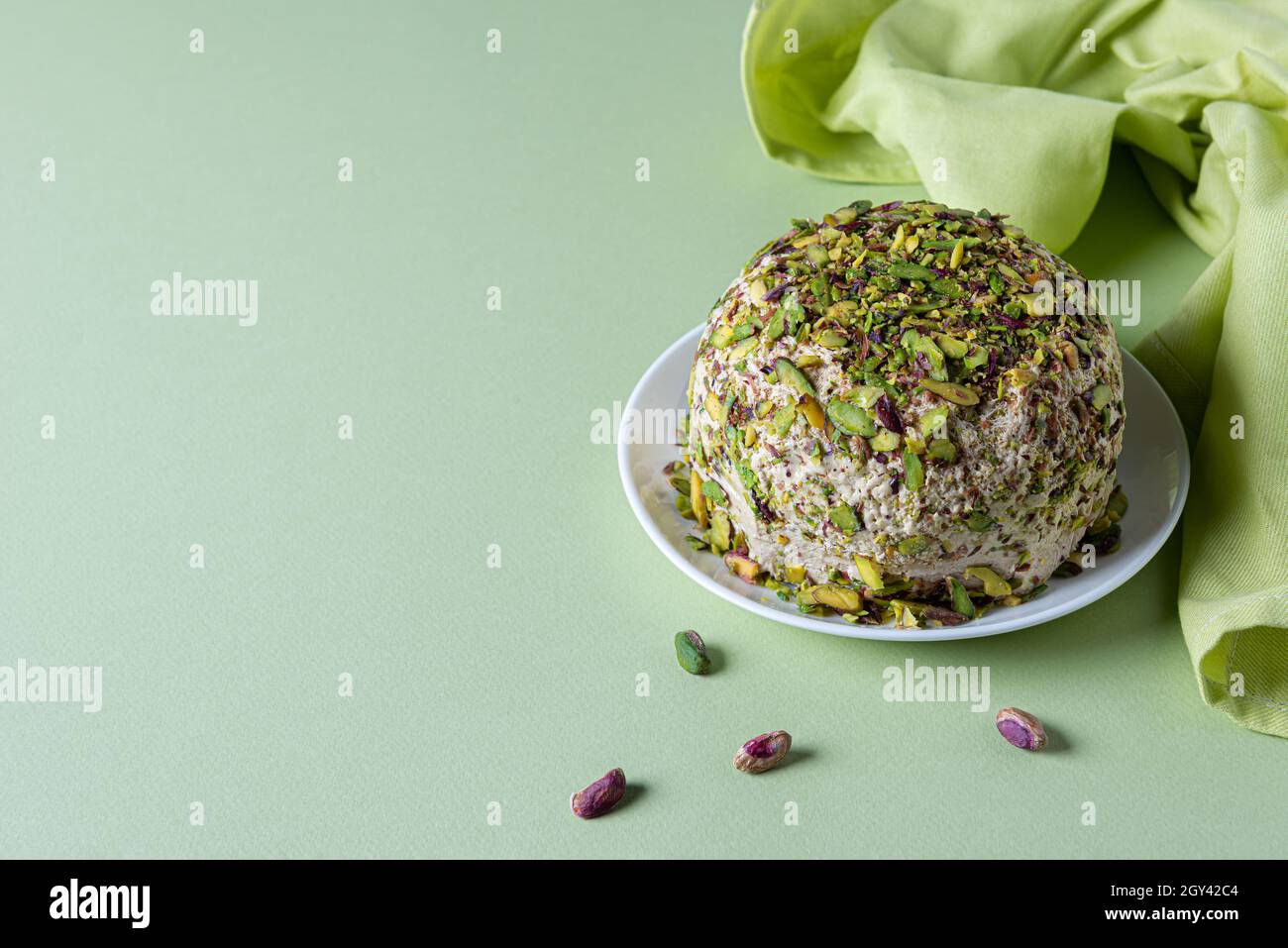 Halva con pistacchi, poche noci sparse e tovagliolo di lino verde su carta verde menta. Orientamento orizzontale. Spazio di copia. Tradizionale medio Oriente Foto Stock