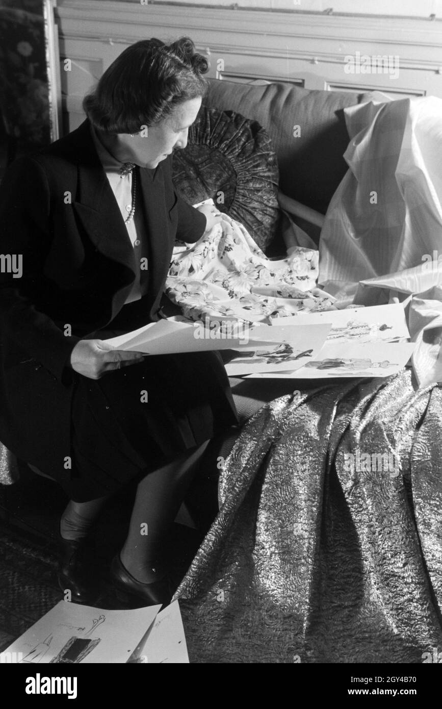 Die Modeschöpferin Nina Carell bei der Sichtung ihrer Entwurfsskizzen, Deutschland ca. 1939. La stilista di moda Nina Carell che glancing sopra i suoi schizzi di disegno, Germania ca. 1939. Foto Stock