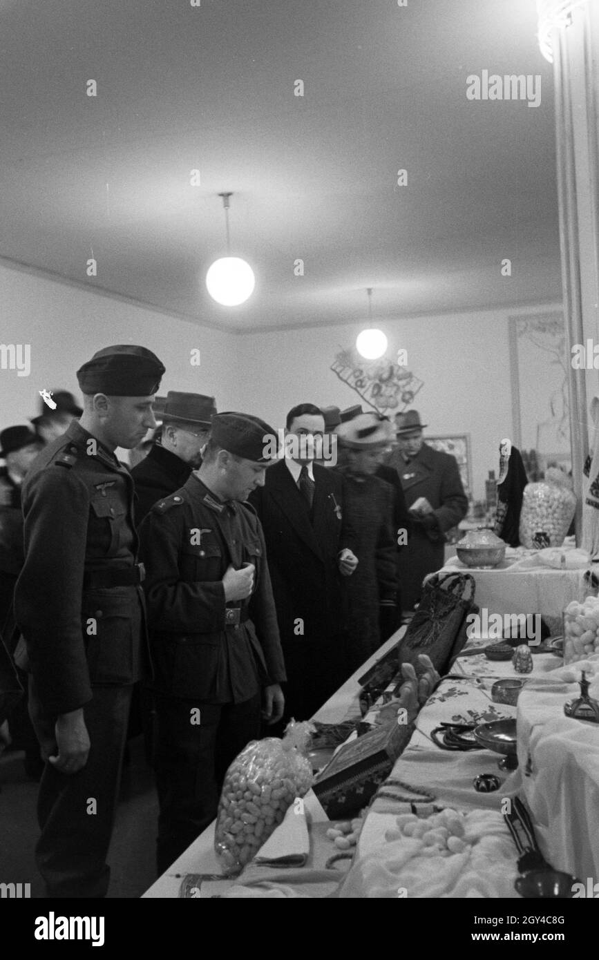 Besucher der Leipziger Frühjahrsmesse vor einem Stand mit Kunsthandwerk; Deutschland 1941. I visitatori della Leipziger Frühjahrsmesse davanti a un cavalletto con artwork; Germania 1941. Foto Stock