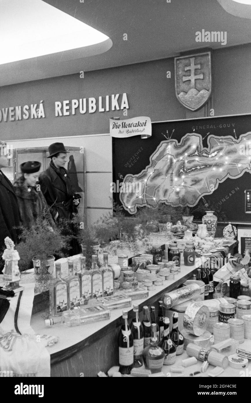 Besucher der Leipziger Frühjahrsmesse an einem Stand mit landestypischen Spezialitäten aus der Slowakei; Deutschland 1941. Visitatori del Leipziger Frühjahrsmesse in uno stand con specialità tradizionali slovacche; Germania 1941. Foto Stock