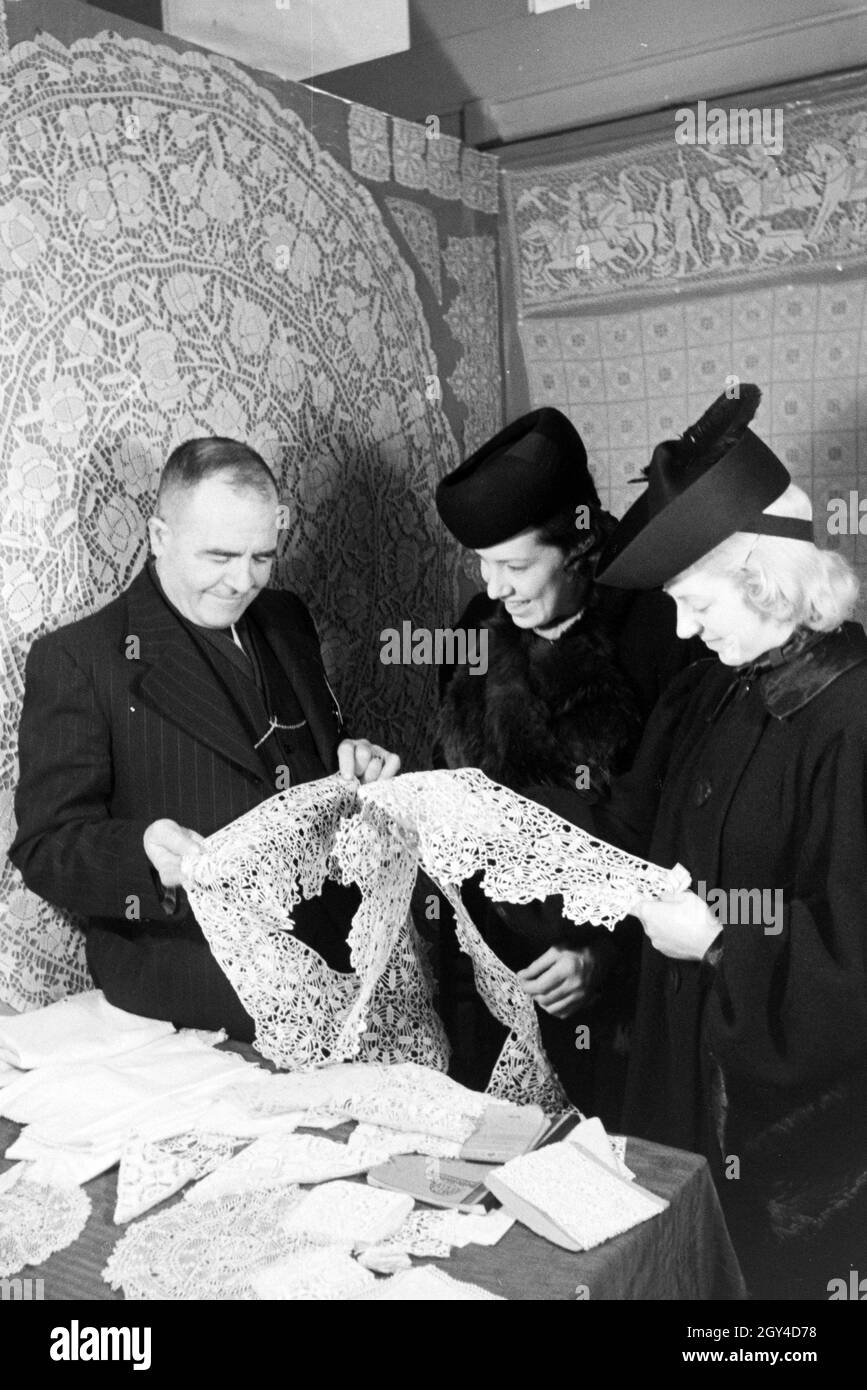 Messebesucher an einem Stand mit Häkelarbeiten, anlässlich der Wiener Modewoche im Haus der Mode ' Palais Lobkowitz', Deutschland 1940er Jahre. Visitatori di una fiera in uno stand con crochet lavoro, in occasione del Wiener Modewoche nella casa della moda 'Palais Lobkowitz', Germania 1940. Foto Stock