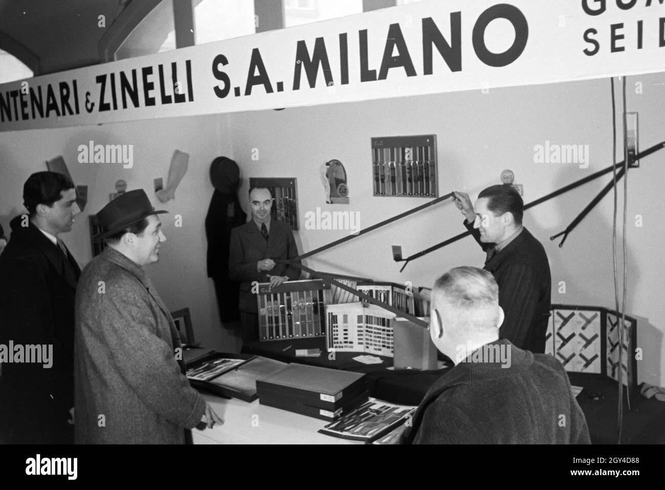 Messebesucher vor einem Stand mit Hosenträgern der italienischen Firma Centenari e Zinelli S.A. Milano, anlässlich der Wiener Modewoche im Haus der Mode ' Palais Lobkowitz', Deutschland 1940er Jahre. Visita ad una fiera di fronte ad una vetrina con i sospensori della società italiana Centenari e Zinelli S.A. Milano, in occasione della Wiener Modewoche nella casa della moda ' Palais Lobkowitz', Germania 1940. Foto Stock