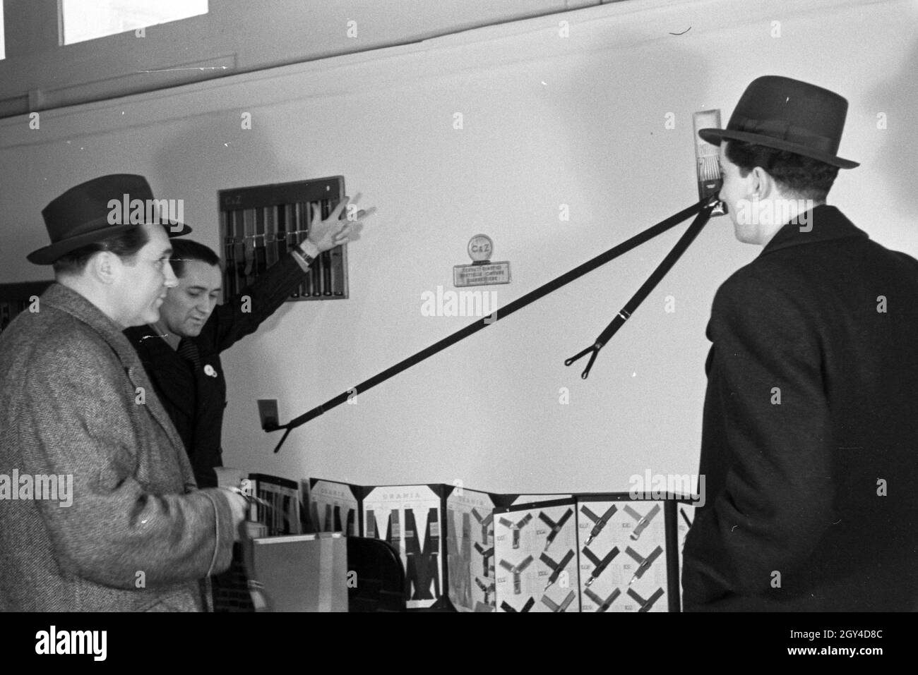 Messebesucher vor einem Stand mit Hosenträgern der italienischen Firma Centenari e Zinelli S.A. Milano, anlässlich der Wiener Modewoche im Haus der Mode ' Palais Lobkowitz', Deutschland 1940er Jahre. Visita ad una fiera di fronte ad una vetrina con i sospensori della società italiana Centenari e Zinelli S.A. Milano, in occasione della Wiener Modewoche nella casa della moda ' Palais Lobkowitz', Germania 1940. Foto Stock