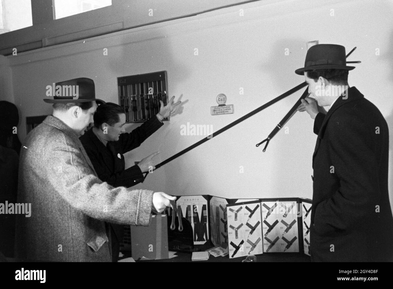 Messebesucher vor einem Stand mit Hosenträgern der italienischen Firma Centenari e Zinelli S.A. Milano, anlässlich der Wiener Modewoche im Haus der Mode ' Palais Lobkowitz', Deutschland 1940er Jahre. Visita ad una fiera di fronte ad una vetrina con i sospensori della società italiana Centenari e Zinelli S.A. Milano, in occasione della Wiener Modewoche nella casa della moda ' Palais Lobkowitz', Germania 1940. Foto Stock