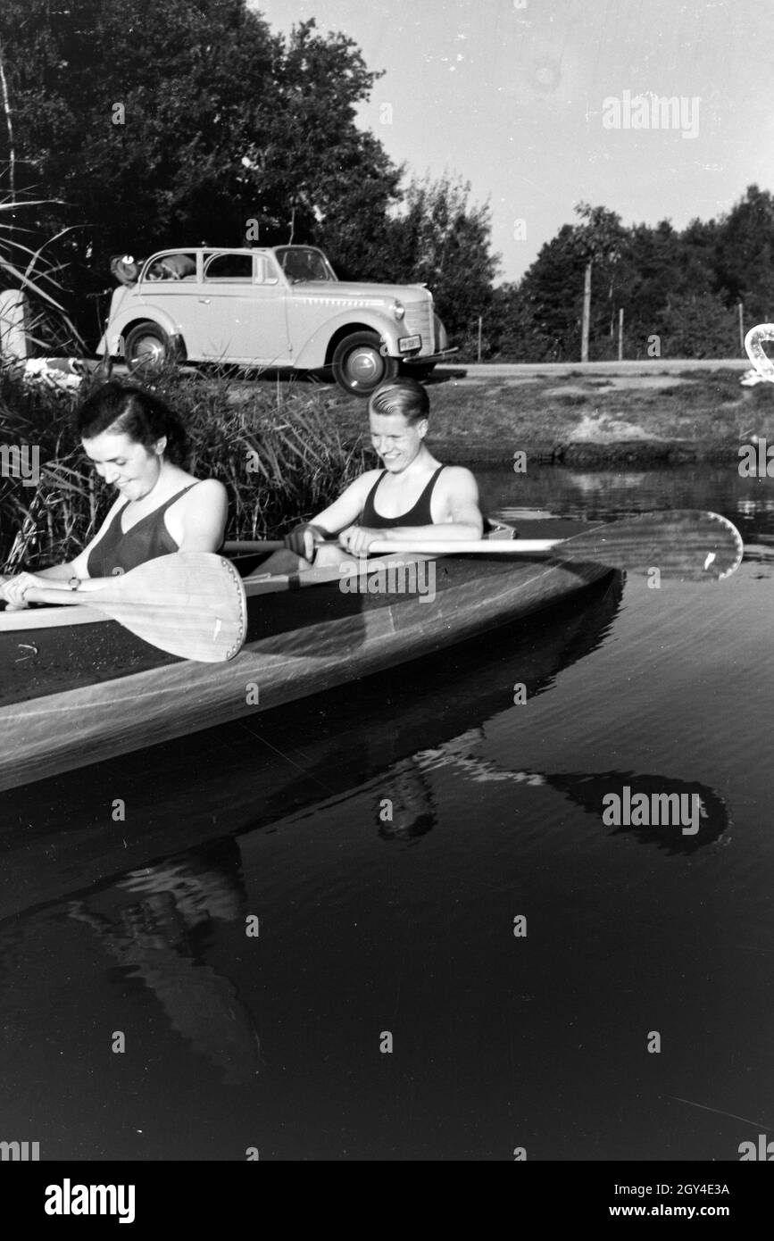 Junges Paar paddelt im Boot in Nähe des Ufers auf einem vedere, Deutschland 1930er jahre. Coppia giovane paddling in una barca sul lago vicino al fiume, Germania 1930s. Foto Stock