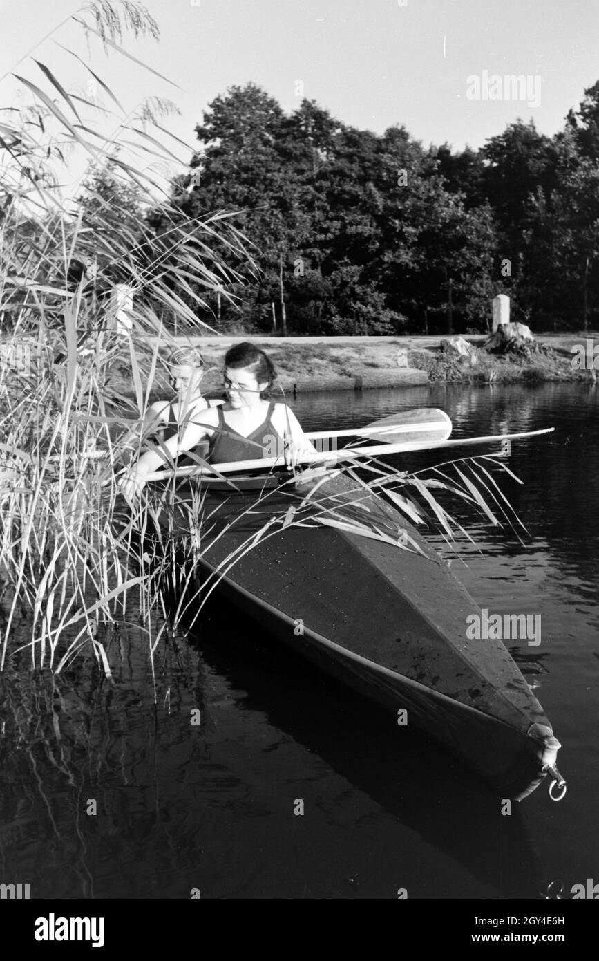 Junges Paar paddelt im Boot in Nähe des Ufers auf einem vedere, Deutschland 1930er Jahre. Coppia giovane paddling in una barca sul lago vicino al fiume, Germania 1930s. Foto Stock