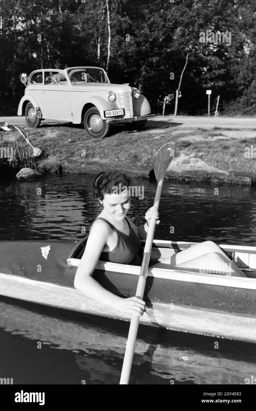 Junge Frau paddelt in einem Boot auf dem vedere nahe des Ufers, Deutschland 1930er. Giovane donna paddling in una barca sul lago vicino al fiume, Germania 1930s. Foto Stock