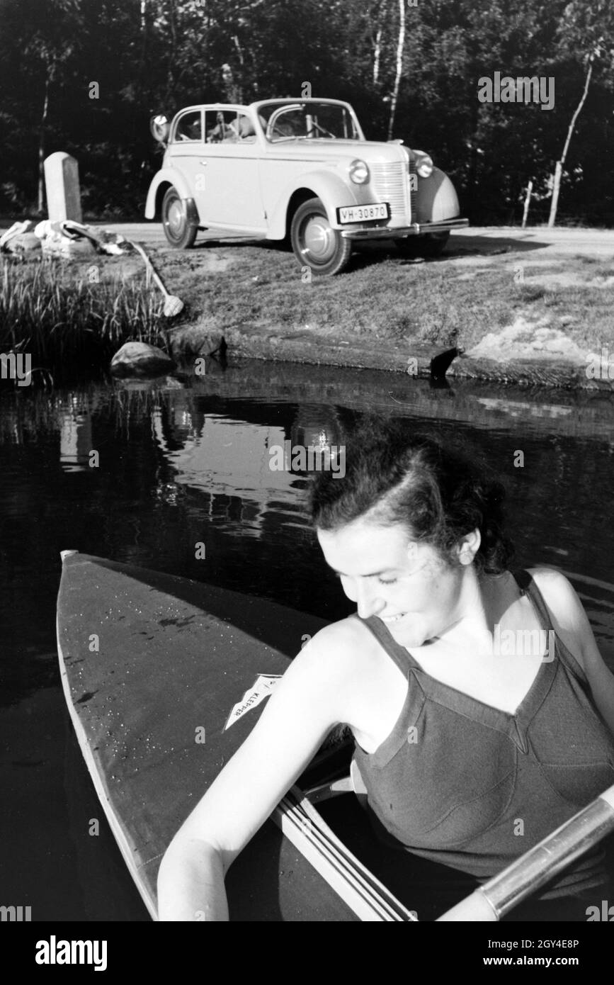 Junge Frau paddelt in einem Boot auf dem vedere nahe des Ufers, Deutschland 1930er. Giovane donna paddling in una barca sul lago vicino al fiume, Germania 1930s. Foto Stock