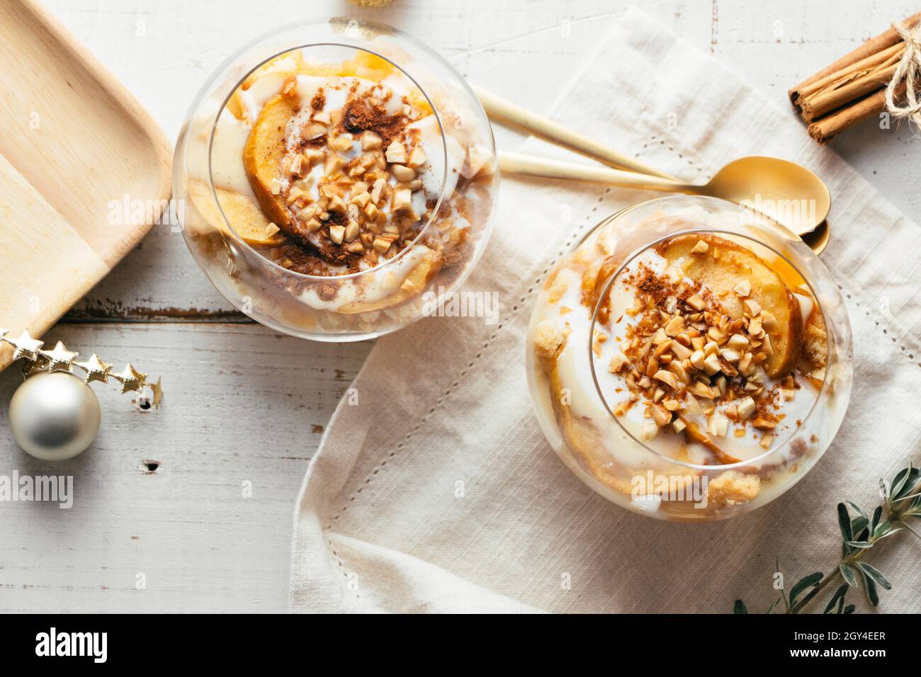 Dessert di Natale in bicchieri di mela al forno, biscotti croccanti alle mandorle, crema pasticcera, marmellata, yogurt, cannella, e mandorle tostate. Parfait. Vista dall'alto Foto Stock