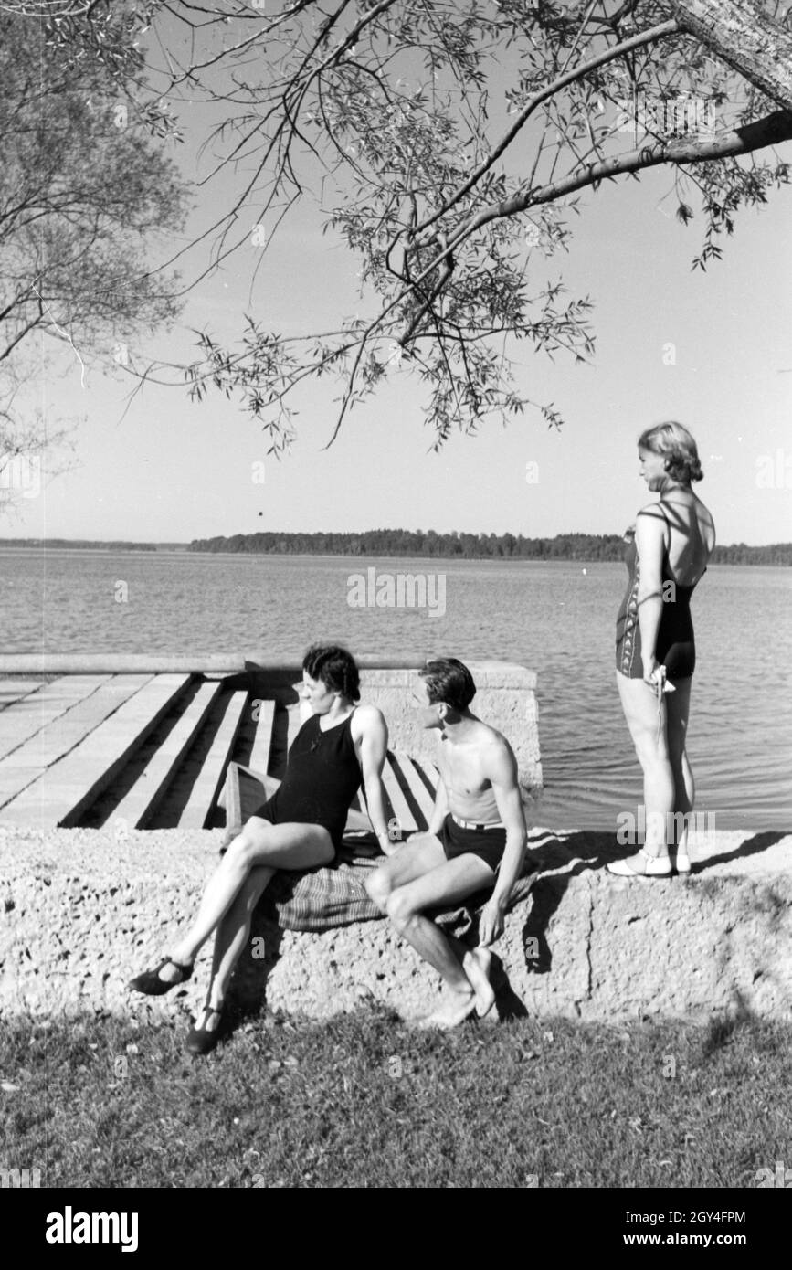 Zwei Junge Frauen und ein junger Mann beim Sonnenbaden und schwimmen im Chiemsee, Deutschland 1930er Jahre. Due giovani donne e un giovane uomo che si prende il sole e nuota nel Chiemsee, Dermany anni trenta. Foto Stock