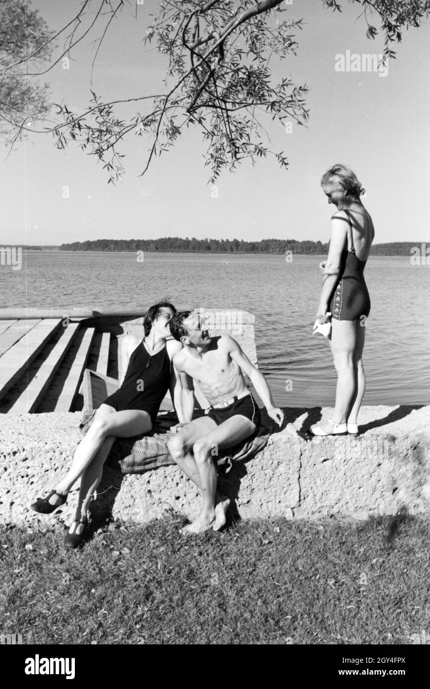 Zwei Junge Frauen und ein junger Mann beim Sonnenbaden und schwimmen im Chiemsee, Deutschland 1930er Jahre. Due giovani donne e un giovane uomo che si prende il sole e nuota nel Chiemsee, Dermany anni trenta. Foto Stock