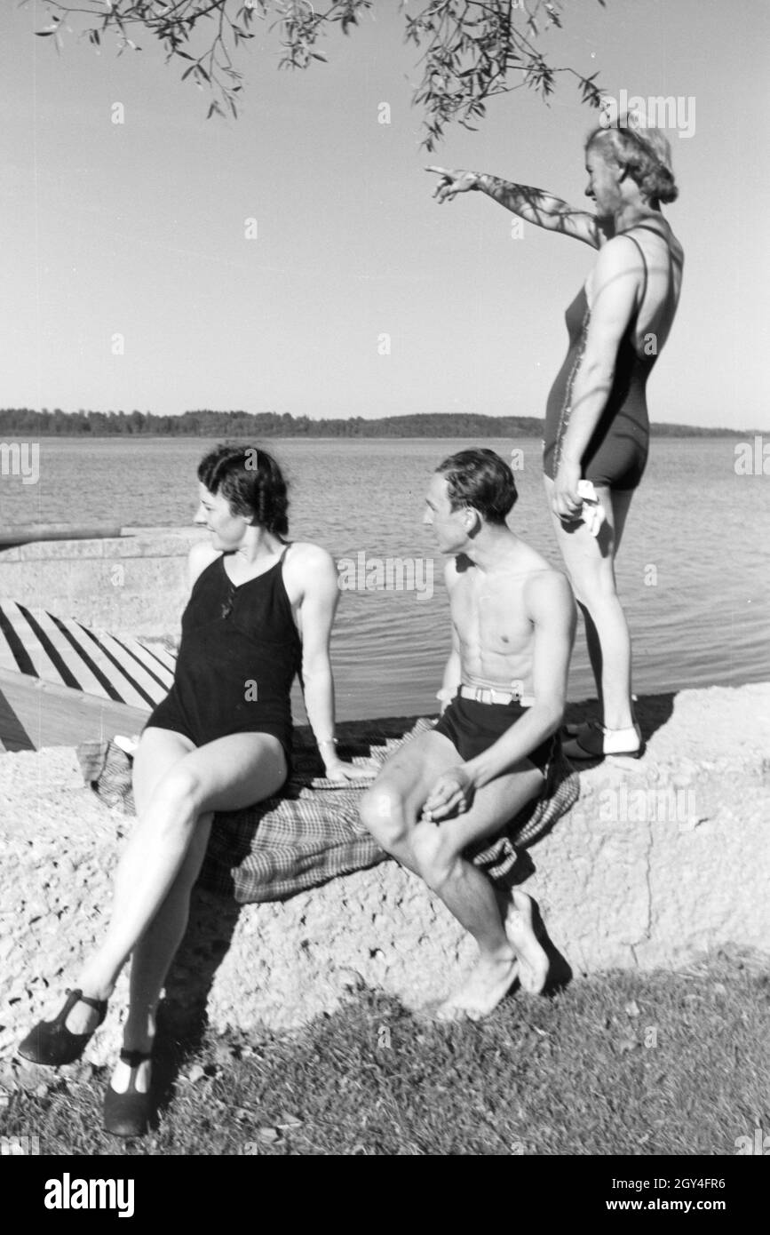 Zwei Junge Frauen und ein junger Mann beim Sonnenbaden und schwimmen im Chiemsee, Deutschland 1930er Jahre. Due giovani donne e un giovane uomo che si prende il sole e nuota nel Chiemsee, Dermany anni trenta. Foto Stock