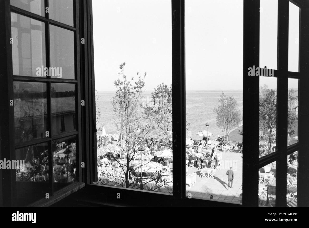 Blick aus einem Fenster auf eine Café Terrasse am Chiemsee, Deutschland 1930er Jahre. Vista dalla finestra su una terrazza caffetteria del Chiemsee, Germania anni trenta. Foto Stock