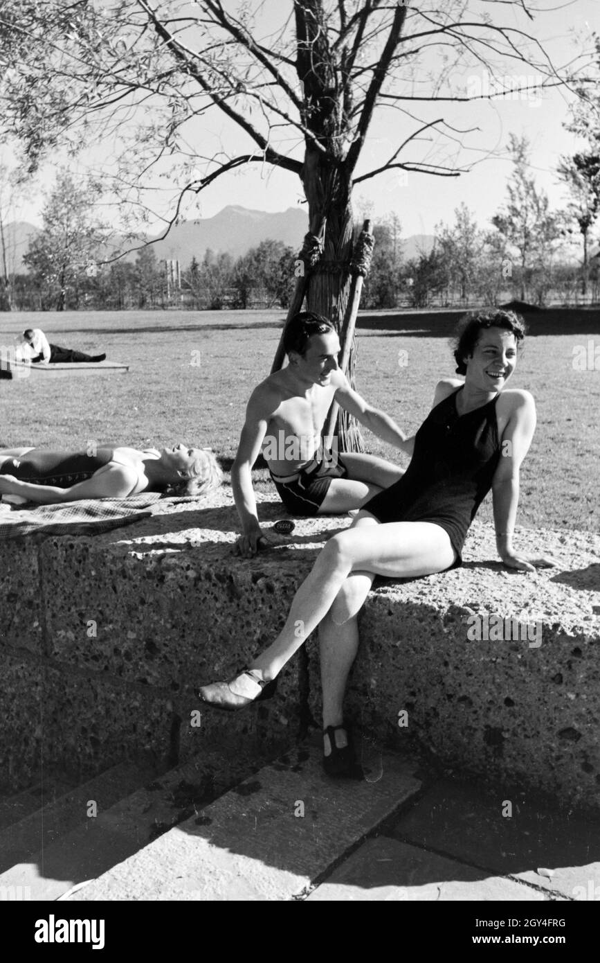Zwei Junge Frauen und ein junger Mann beim Sonnenbaden und schwimmen im Chiemsee, Deutschland 1930er Jahre. Due giovani donne e un giovane uomo che si prende il sole e nuota nel Chiemsee, Dermany anni trenta. Foto Stock