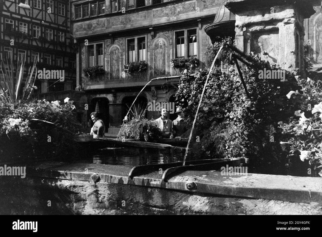 Neben dem Rathaus ist auch der mit Blumen geschmückte Springbrunnen eine Sehenswürdigkeit Am Marktplatz von Tübingen, Deutschland 1930er Jahre. Oltre al municipio, la fontana decorata con fiori è un altro oggetto di interesse presso la piazza del mercato di Tübingen, Germania 1930s. Foto Stock