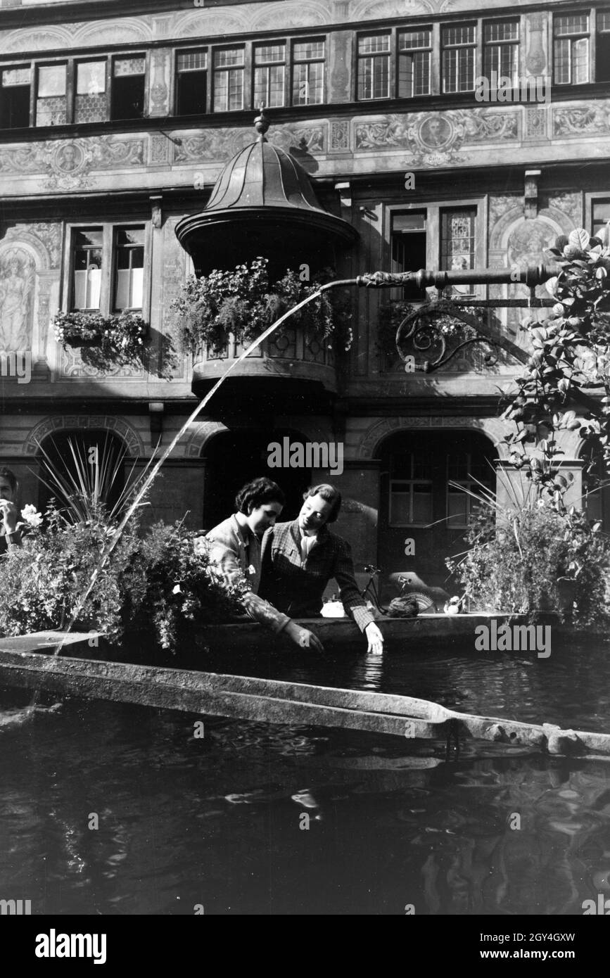 Neben dem Rathaus ist auch der mit Blumen geschmückte Springbrunnen eine Sehenswürdigkeit Am Marktplatz von Tübingen, Deutschland 1930er Jahre. Oltre al municipio, la fontana decorata con fiori è un altro oggetto di interesse presso la piazza del mercato di Tübingen, Germania 1930s. Foto Stock