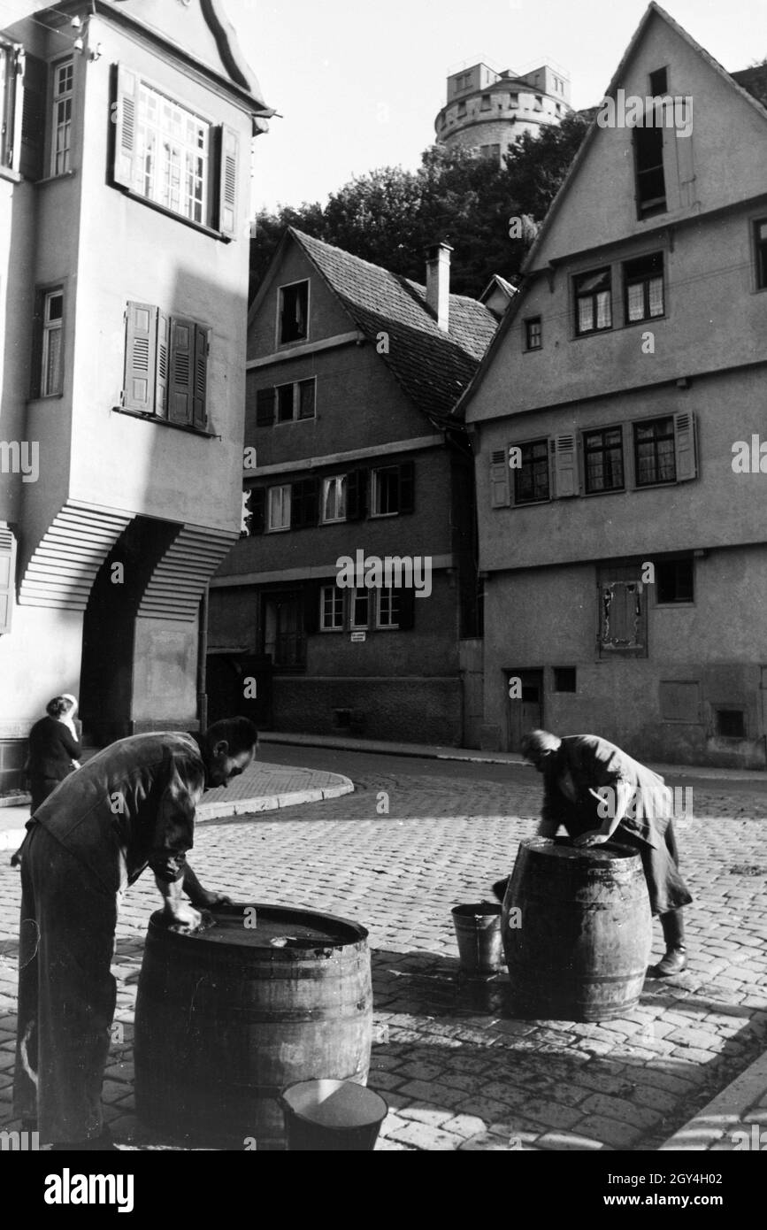 Zwei Männer auf einer der Straßen der Altstadt bei der Reinigung großer Holzfässer, Tübingen, Deutschland 1930er Jahre. Due uomini lavaggio grosse botti di legno su una delle strade del quartiere storico di Tübingen, Germania 1930s. Foto Stock