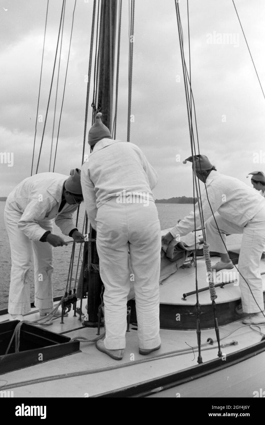 Eine Gruppe Segler bereitet das Segel des Bootes vor, Cheimsee, Deutschland 1930er Jahre. Un gruppo di marinai si sta preparando la tela sulla barca, Chiemsee, Germania 1930s. Foto Stock