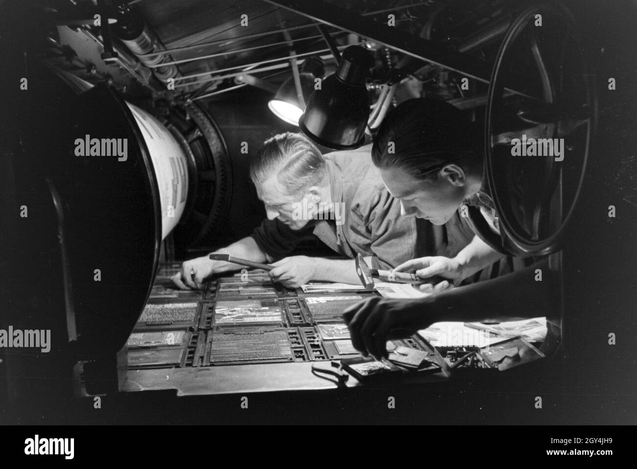 Zwei Drucker setzen letteran zu einem Schriftstatz un einer Rotationsdruckmaschine zusammen, Deutschland 1930er Jahre. Due stampanti sono disponendo di tipo metallico ordina rotative da stampa, Germania 1930s. Foto Stock