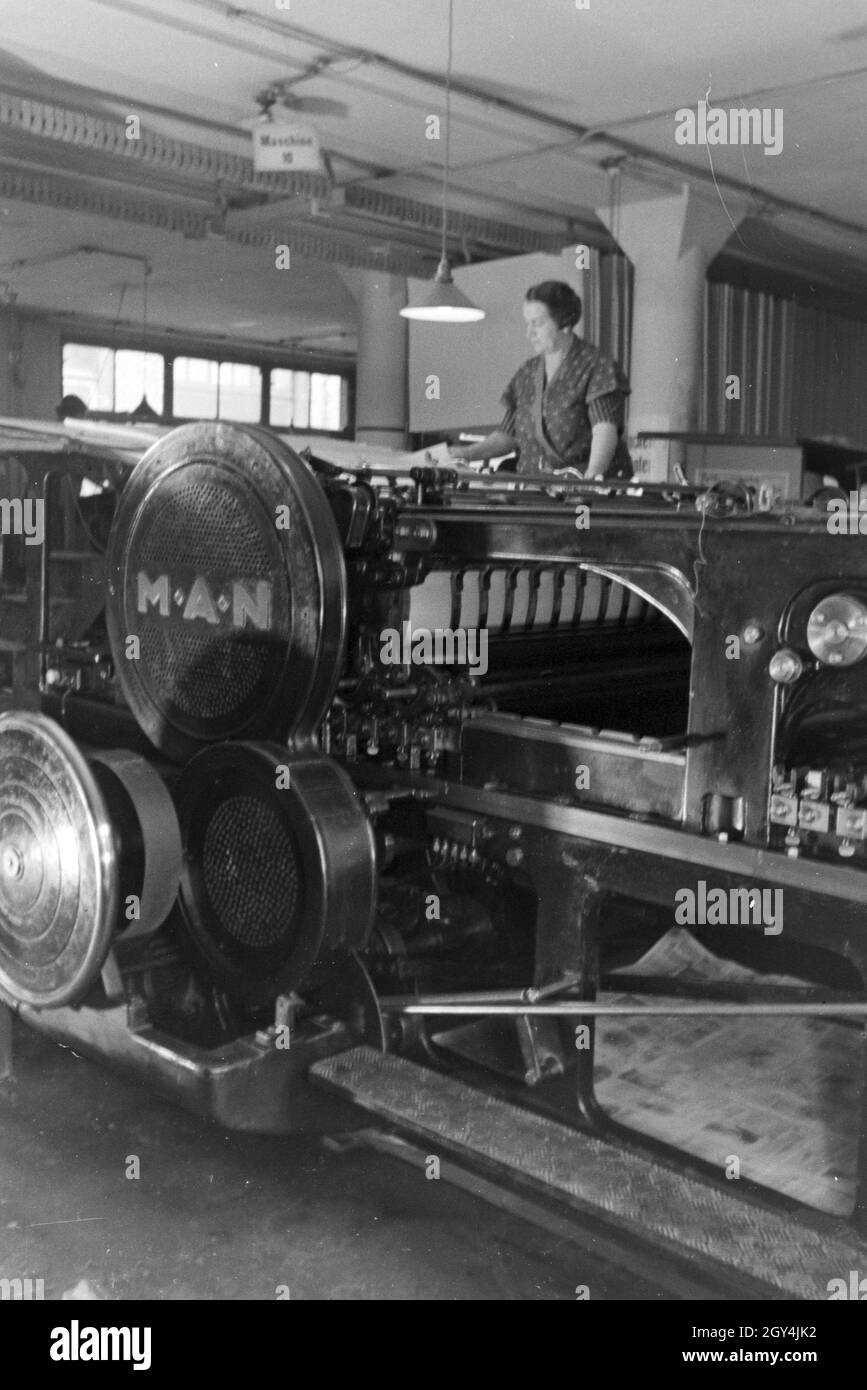 Eine Druckereimitarbeiterin legt die bedruckten Papierbögen in eine Planschneidemaschine, produziert vom Maschinenbaukonzern MAN (Maschinenfabrik Augsburg-Nürnberg), Deutschland 1930er Jahre. Un lavoratore in una printery sta mettendo la carta stampata in fogli all'interno di una macchina di taglio, che viene prodotta mediante l'ingegneria meccanica azienda MAN (Maschinenfabrik Augsburg-Nürnberg), Germania 1930s. Foto Stock