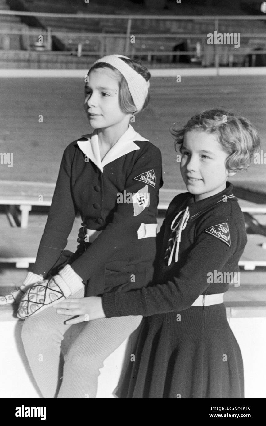 Porträt von zwei BDM Kindereisläuferinnen mit den Hitlerjugend Aufnähern und Hakenkreuzemblem dem auf der Kleidung, Deutschland 1930er Jahre. Ritratto di due bambini BDM figureskaters con la Gioventù Hitleriana patch e la svastica emblema sulla loro abbigliamento, Germania 1930s. Foto Stock