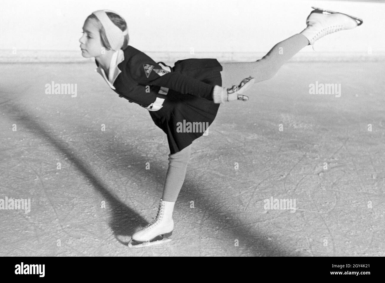 Eine BDM Kindereisläuferin mit den Hitlerjugend Aufnähern und Hakenkreuzemblem dem auf der Kleidung während eines corsi mit dem österreichischen Eiskunstläufer und Olympiasieger Karl Schäfer, Deutschland 1930er Jahre. Un BDM bambini figureskaters con la Gioventù Hitleriana patch e la svastica simbolo sul suo abbigliamento durante un allenamento con il figureskater austriaco e alle Olimpiadi champion Karl Schäfer, Germania 1930s. Foto Stock