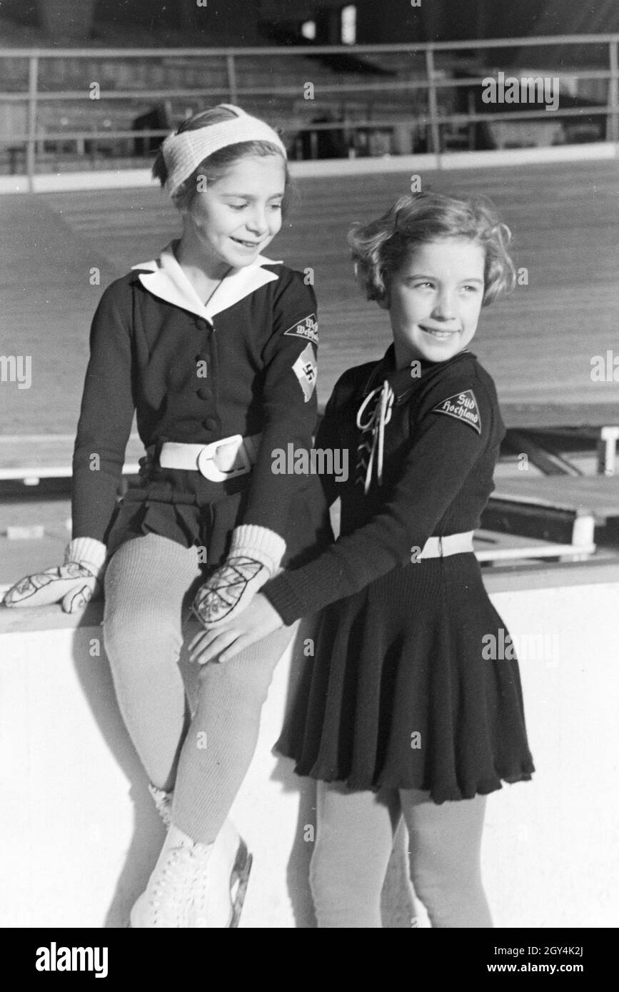 Porträt von zwei BDM Kindereisläuferinnen mit den Hitlerjugend Aufnähern und Hakenkreuzemblem dem auf der Kleidung, Deutschland 1930er Jahre. Ritratto di due bambini BDM figureskaters con la Gioventù Hitleriana patch e la svastica emblema sulla loro abbigliamento, Germania 1930s. Foto Stock