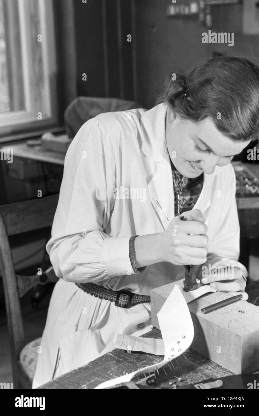 Eine Frau punziert verschiedene Lederwaren, Deutsches Reich 1930er Jahre. Donna punchinging diversi prodotti in cuoio, Germania 1930s. Foto Stock