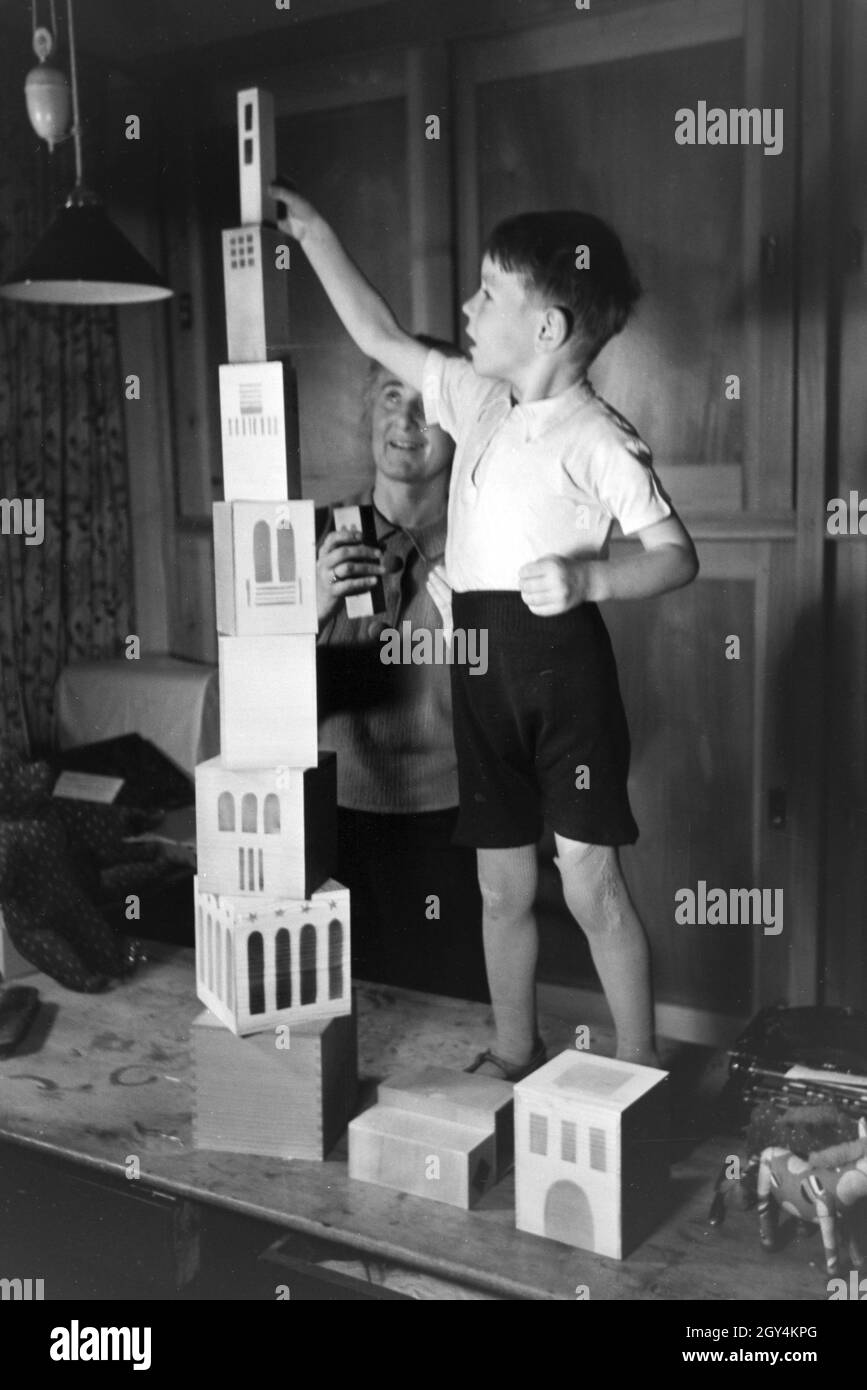 Eine Kunsthandwerkerin zeigt einem Jungen neue Spielsachen, Deutsches Reich 1930er Jahre. Un artigiano che mostra i nuovi giocattoli, Germania 1930s. Foto Stock