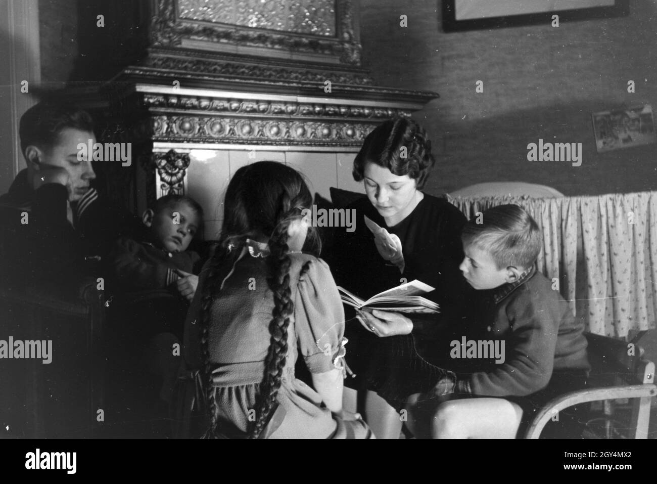 Mitglieder einer kinderreichen Familie lesen gemeinsam ein Buch, Deutsches Reich 1930er Jahre. I membri di una famiglia estesa la lettura di un libro insieme, Germania 1930s. Foto Stock