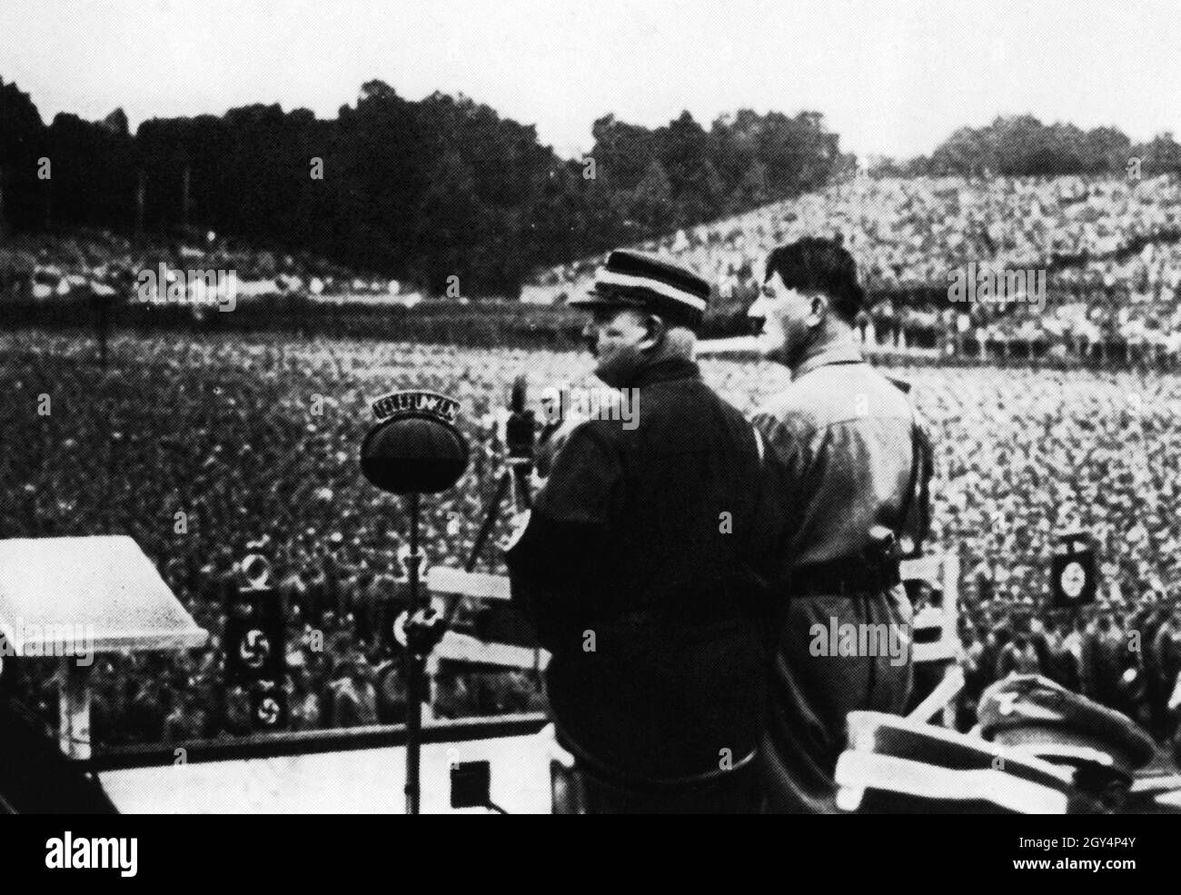 Adolf Hitler ed Ernst Röhm si alzano sul podio davanti all'enorme folla che si è radunata nella Luitpoldarena del partito nazista Rally Grounds a Norimberga per assistere allo spiegamento di SA stormers nel Luitpoldarena. [traduzione automatizzata] Foto Stock