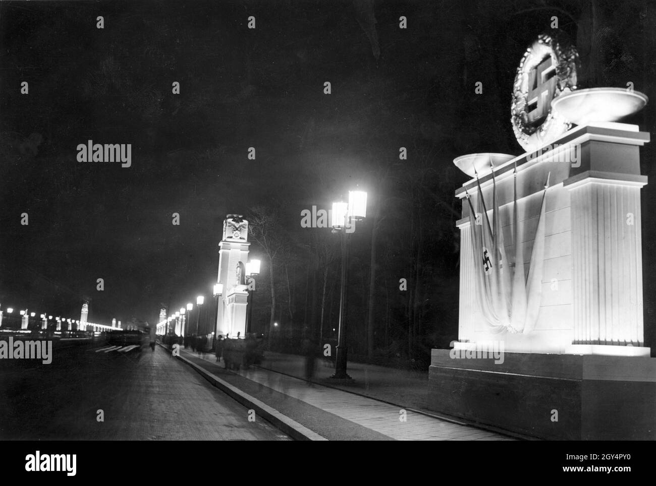 L'asse est-ovest (oggi: Straße des 17. Juni) a Berlino-Mitte è luminoso da luci di strada nel 1939. Vari simboli nazisti su colonne monumentali fiancheggiano la strada. [traduzione automatizzata] Foto Stock