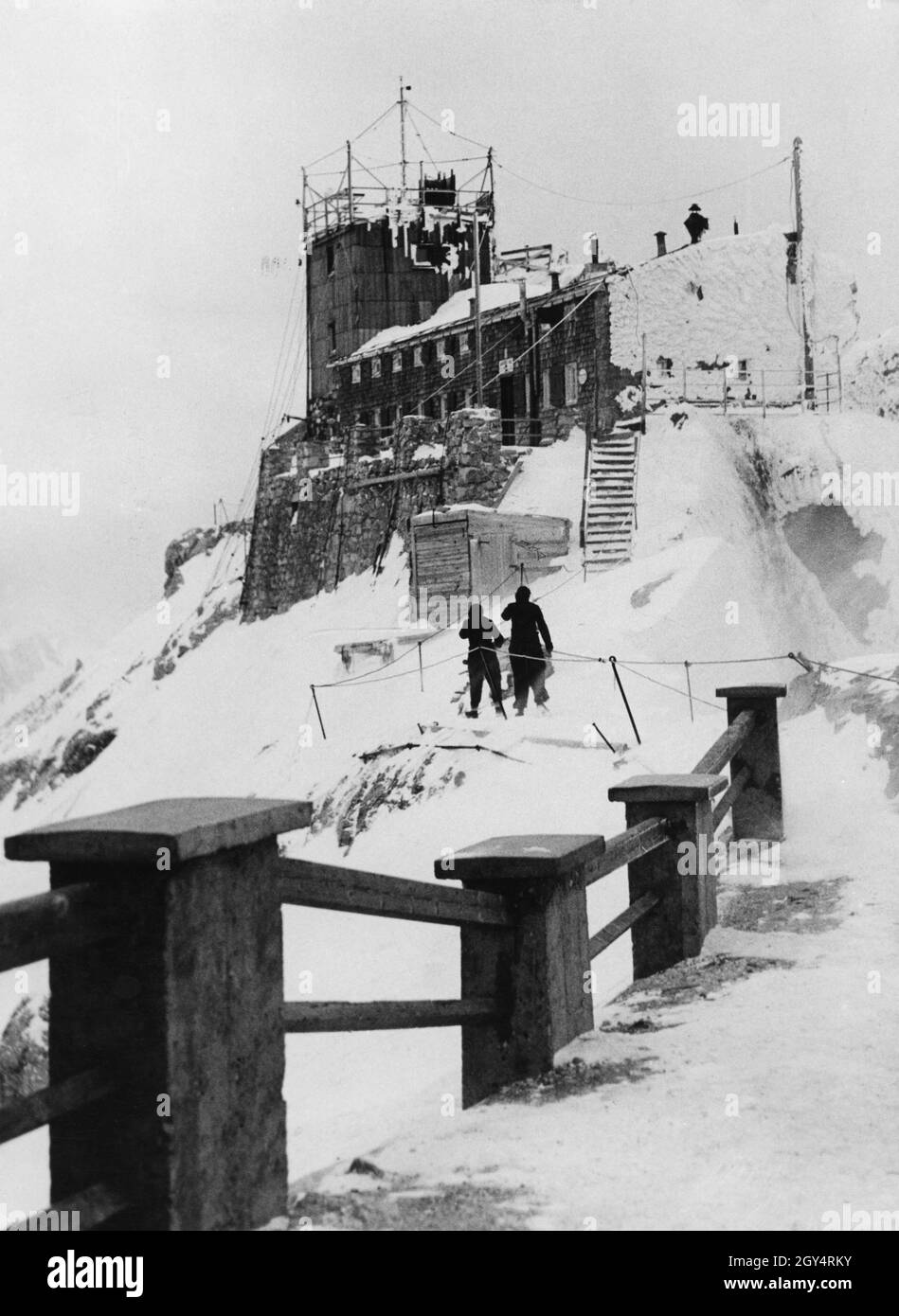 Due persone combattono per la Münchner Haus sulla Zugspitze nell'inverno del 1938 con neve e vento ghiacciato. L'ultima parte del percorso è difficilmente garantita. Presumibilmente lavorano alla stazione meteorologica, che si trova nella torre. [traduzione automatizzata] Foto Stock