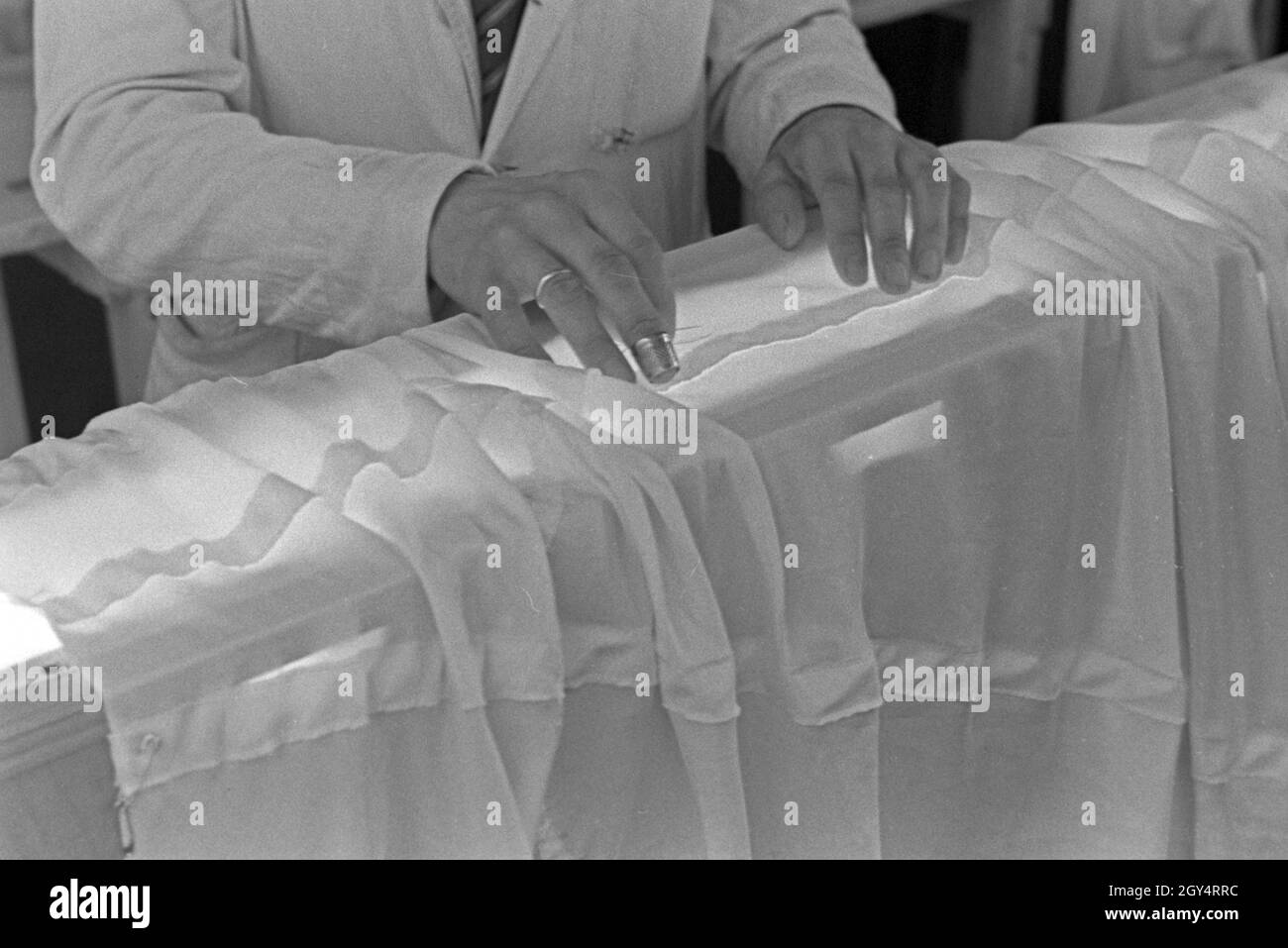 Hände des Vorarbeiters in einer Fallschirm Näherei, Deutschland 1940er Jahre. Le mani di un headman ad un paracadute di fabbrica di cucitura, Germania 1940s. Foto Stock