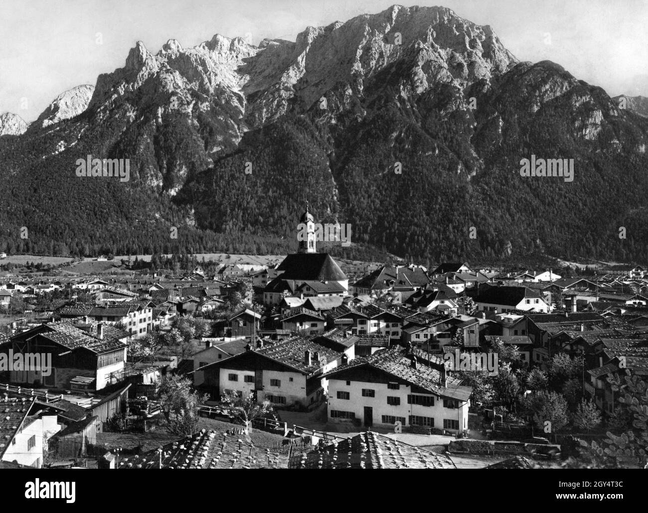 Questa fotografia, scattata intorno al 1930, mostra Mittenwald con la chiesa di San Pietro e Paolo al centro. Dietro il villaggio sorge la catena del Karwendel settentrionale con Karwendelkopf, Karwendelspitze e Linderspitze. [traduzione automatizzata] Foto Stock