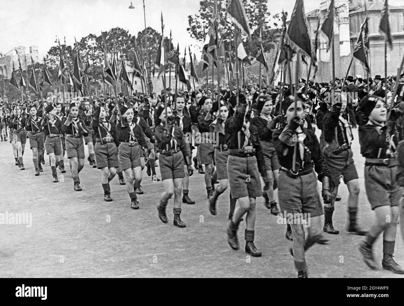 Ragazzi dell'organizzazione fascista per la gioventù Opera Nazionale Balilla marciano in una sfilata in Italia nel 1936, tenendo i loro pennanti in alto. [traduzione automatizzata] Foto Stock