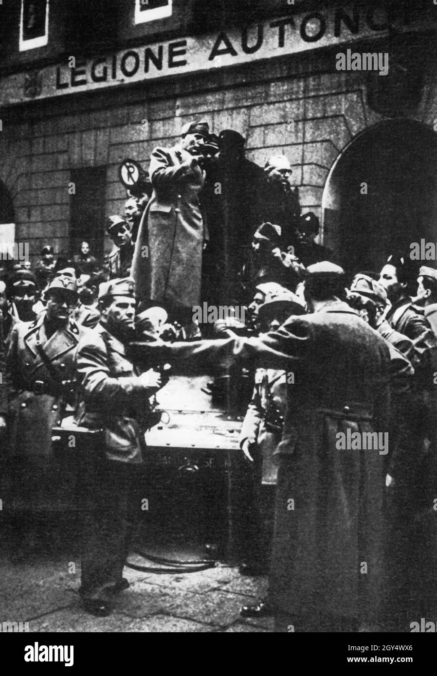 'Benito Mussolini, dittatore estromesso d'Italia e reinsediato come capo di stato della Repubblica sociale Italiana, si eleva in questo dipinto e parla ad un compagno. Egli è circondato dai suoi fedeli, che continuano a seguirlo. La fotografia è stata scattata a Milano nell'aprile 1945, prima del volo di Mussolini dalla città il 25 aprile. Si trova in via Rovello, angolo di via Dante, di fronte all'edificio e alla casa principale della ''Lega Autonoma Mobile Ettore Muti''. Oggi ospita il piccolo Teatro di Milano. [traduzione automatizzata]' Foto Stock