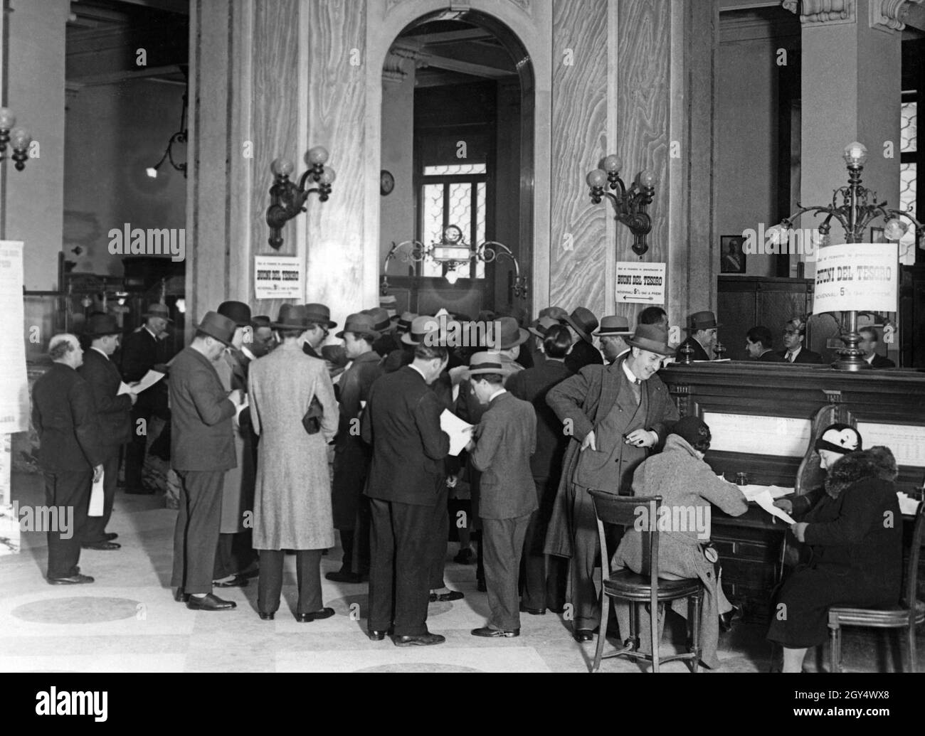Il 1° aprile 1932, le filiali di banca erano affollate, come qui ai banchi di una banca romana. La gente si iscrive in liste per riservare le banconote del tesoro di nove anni (buoni del tesoro novennali), che sarebbero state emesse in una data successiva. [traduzione automatizzata] Foto Stock
