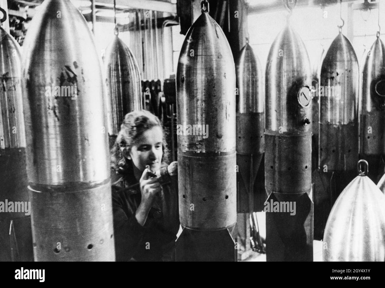 Industria degli armamenti nella seconda guerra mondiale: Un operaio mette numeri di tipo sulle bombe aeree finite. [traduzione automatizzata] Foto Stock
