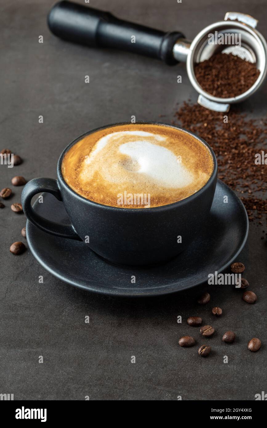 Caffè latte rilassante in una tazza di porcellana nera su un tavolo in pietra Foto Stock