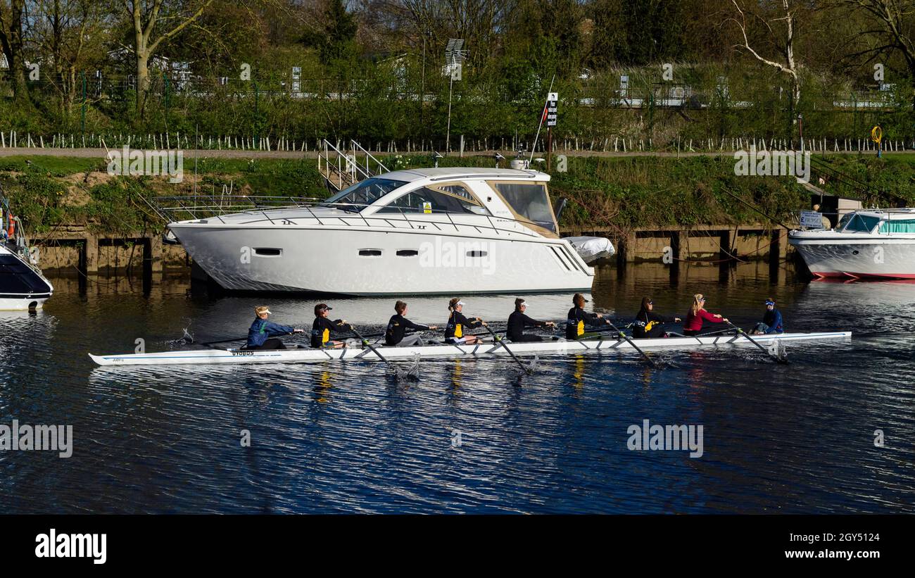 Adolescenti in barca (canottaggio 8 in sessione di pratica, imparare a fila) passando le barche al fiume ormings - Sunny River Ouse, North Yorkshire, Inghilterra Regno Unito. Foto Stock